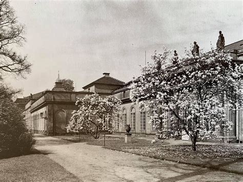 an old black and white photo of a building with trees in the foreground,