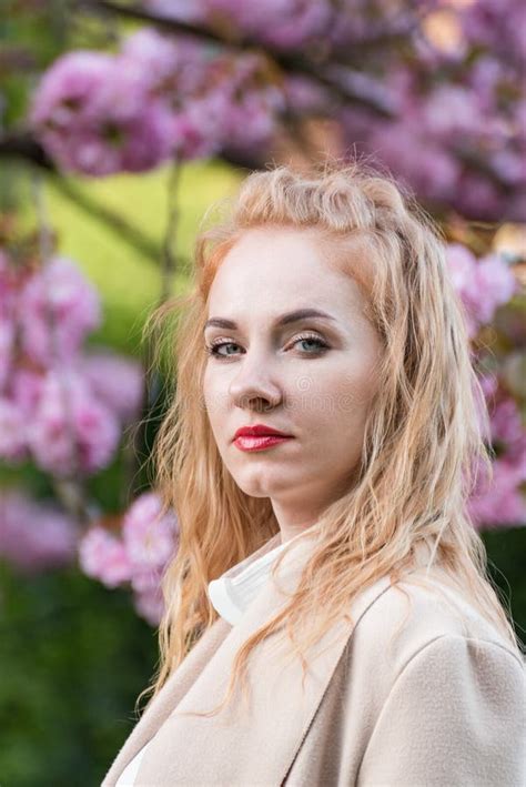 Successful Business Woman Outdoors Portrait Of Blonde Woman With Red Lips Near Blossom Tree