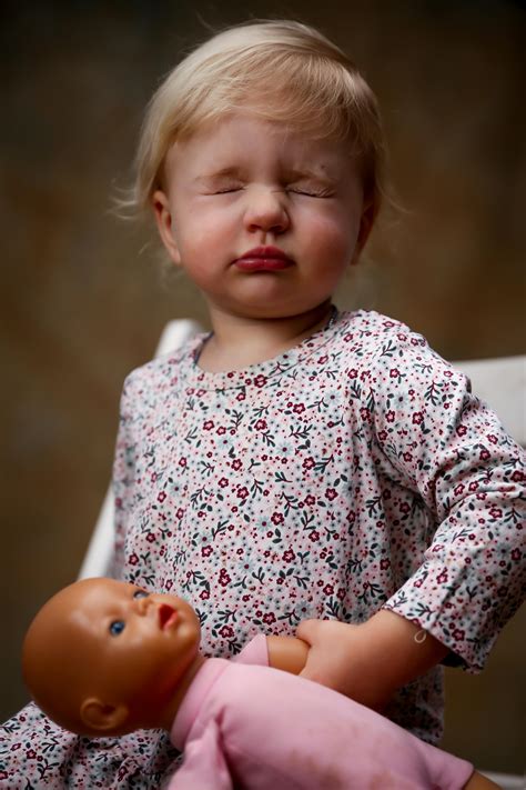 Toddler Wearing Floral Dress Holding Doll · Free Stock Photo