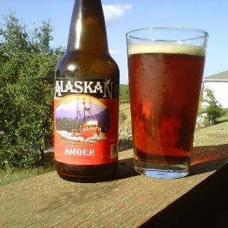 A Beer Bottle Next To A Glass Filled With Liquid On A Wooden Table In