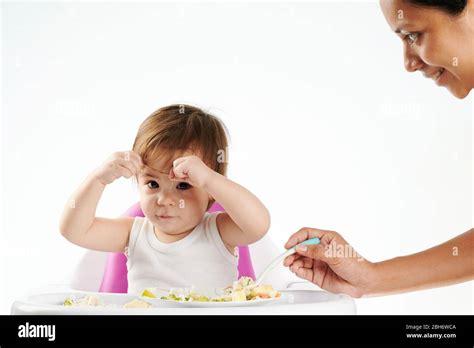 Funny baby girl playing while eating isolated on studio background Stock Photo - Alamy