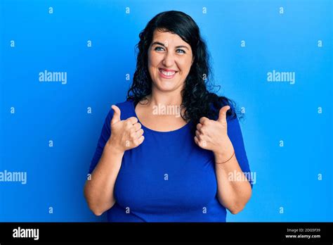 Plus Size Brunette Woman Wearing Casual Blue Shirt Success Sign Doing Positive Gesture With Hand