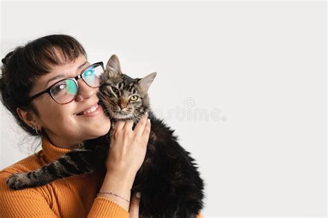 Una Mujer Latina Con Anteojos Sostiene A Su Gato De Tabby Mientras Sonr E Y Mira La C Mara