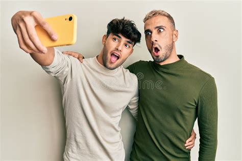 Homosexual Gay Couple Standing Together Taking A Selfie Photo With Smartphone Scared And Amazed