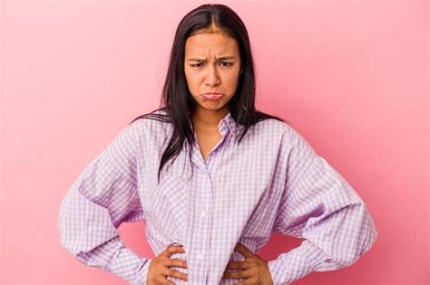 Joven mujer latina aislada sobre fondo rosa cara triste y seria sintiéndose miserable y