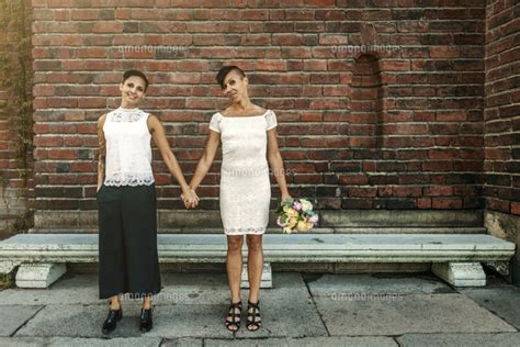 Happy Newlywed Lesbian Couple Standing Against Brick Wall[11081013772]の写真素材・イラスト素材｜アマナイメージズ