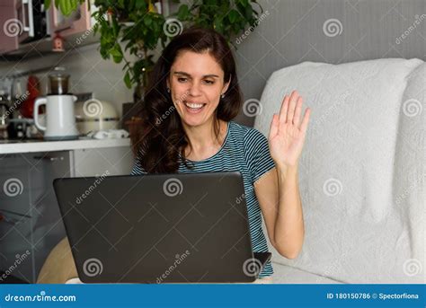 Brunette Girl Waves Her Hand Says Hi And Looks At Her Laptop Making Video Call In Her Apartment