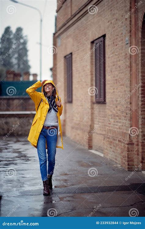 A Young Handsome Woman In A Yellow Raincoat Is Enjoying A Rain While Walking The City Walk