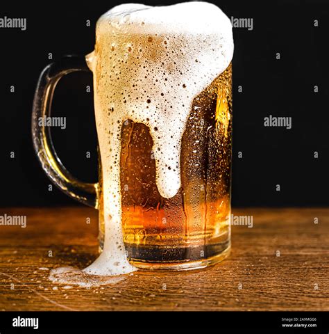 Cold Beer With Foam In A Mug On A Wooden Table And A Dark Background