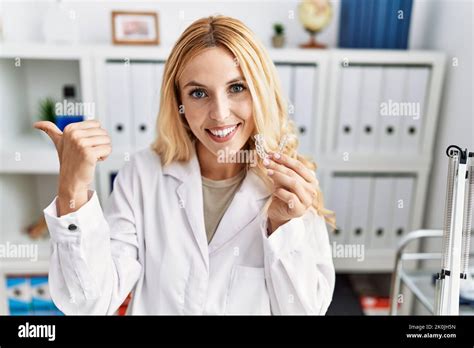 Beautiful Blonde Dentist Woman Holding Invisible Aligner Orthodontic At Dental Clinic Pointing