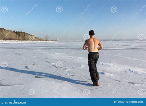 Man In A Cap With A Naked Torso Running Across The Ice Of A Frozen