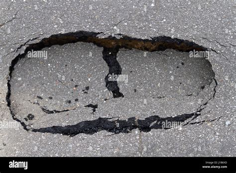 Close Up Of A Small Asphalt Sinkhole In The Road Shaped Like A Big