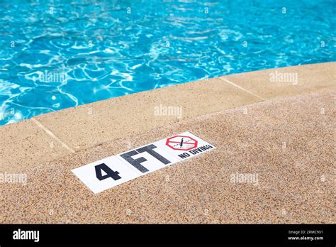 Edge of swimming pool with no diving warning sign and 4 foot depth marker Stock Photo - Alamy