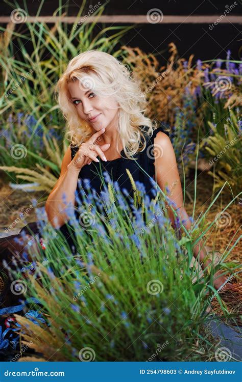 A Beautiful Middle Aged Blonde Woman In A Black Dress In Lavender Bushes Stock Image Image Of