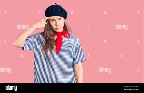 Junge schöne blonde Frau trägt französisch Baskenmütze und gestreiften T Shirt zeigt unglücklich