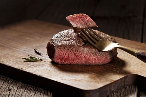 A Piece Of Steak On A Cutting Board With A Fork