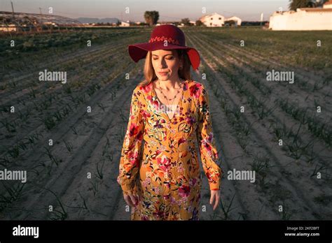 Blonde Caucasian Mature Woman In A Flowery Dress With Her Eyes Closed Standing In The Middle Of