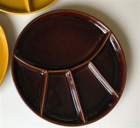 Three Yellow Plates And One Brown Plate On A White Table Top With The