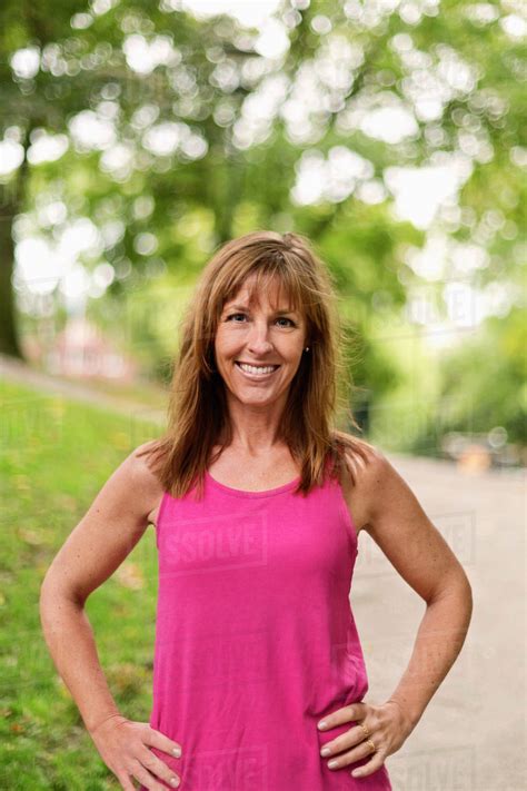 Portrait Of Happy Fit Mature Woman Standing With Hands On Hips At Park Royalty Free Stock