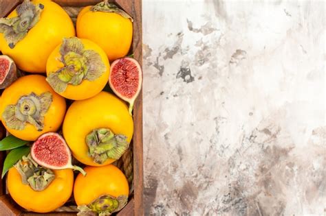 Vue rapprochée des figues de kakis fraîches dans une boîte en bois sur fond nude Photo Gratuite