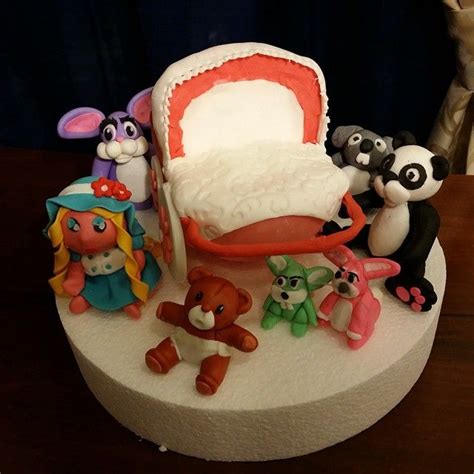 There Is A Cake With Many Toys On The Top Of It Including An Infant S Crib