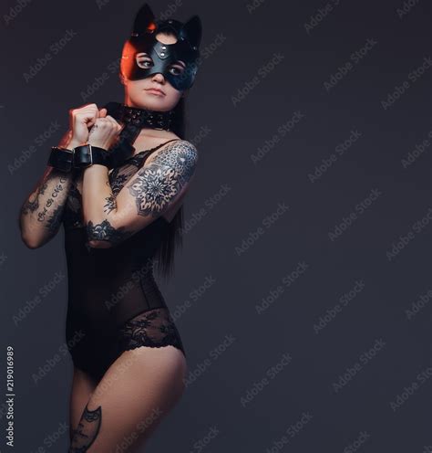 Sexy Woman Wearing Black Lingerie In BDSM Cat Leather Mask And Accessories Posing On Dark