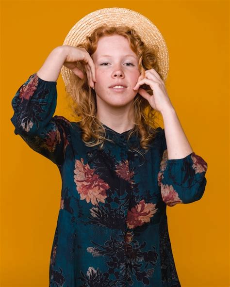 Hembra pelirroja joven en la presentación del sombrero y del vestido