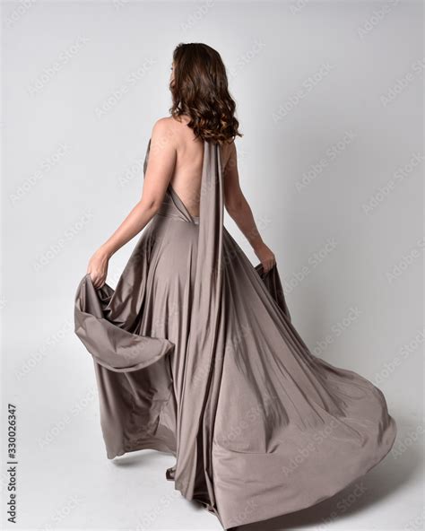 Portrait Of A Pretty Brunette Girl Wearing A Long Silver Evening Gown Full Length Standing Pose
