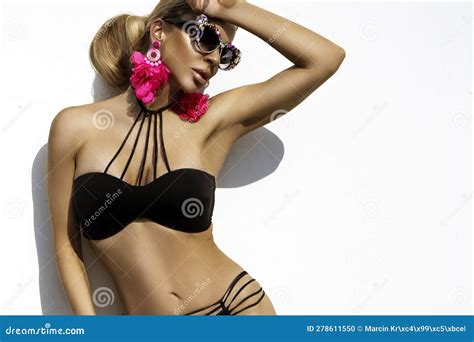 Woman Is Wearing Elegant Bikini And Luxury Sunglasses And Is Posing On White Wall On Summer Day
