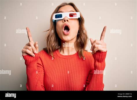 Das junge blonde Mädchen das eine 3D Kinogläser über isoliertem Hintergrund trägt staunte und