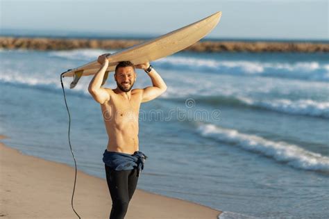 A Smiling Man Surfer With Naked Torso Holding A Surfing Board Over His Head Stock Photo Image