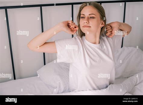 Waking Up In The Morning Young Sleepy Woman Stretches Out In Bed With