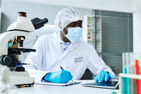 Adult Black Man As Scientist Using Laptop Doing Research In Laboratory