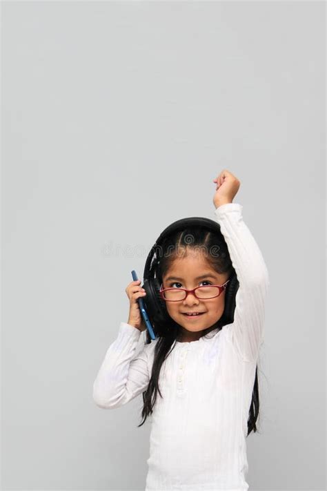 4 Year Old Brunette Latin Girl With Glasses Listens To Music In Her Headphones Connected To Her