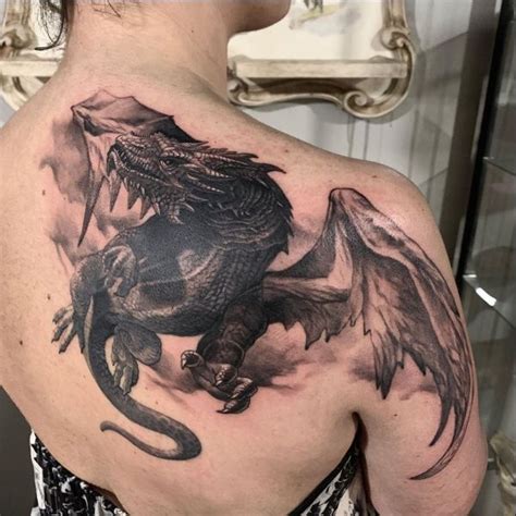 The Back Of A Man S Shoulder With A Black Dragon Tattoo On His Chest