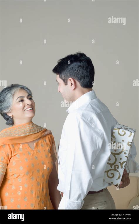 Mature Woman Standing In Front Of Her Son Hiding A Gift Behind His Back Stock Photo Alamy