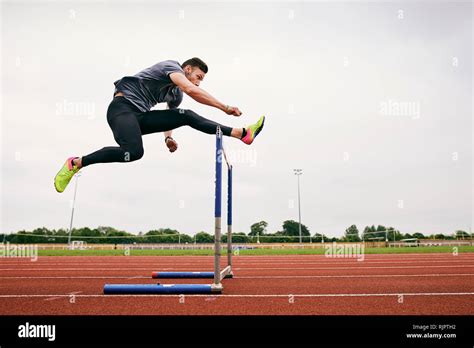 Athlete Jumping Over Hurdle On Running Track Stock Photo Alamy