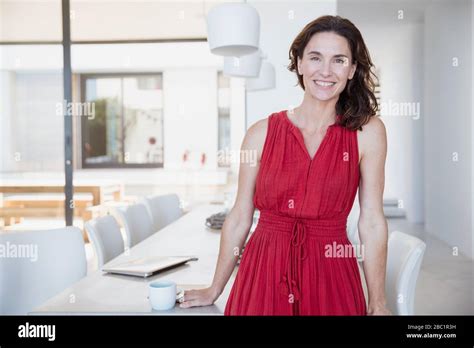 Portrait Smiling Confident Brunette Woman In Red Dress In Dining Room Stock Photo Alamy