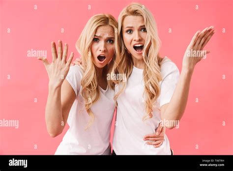 Shocked Confused Blonde Twins Wearing In T Shirts Gesturing And Looking At The Camera Over Pink