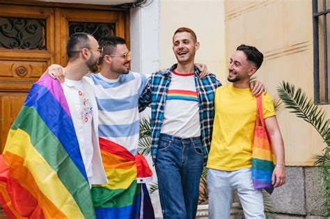 Vibrante cuarteto alegres amigos gay abrazan el orgullo lgbtq con banderas bolsas camisas más