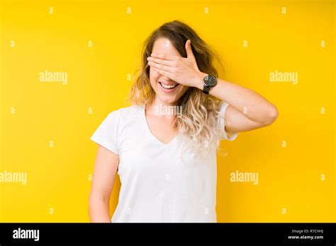 Junge hübsche blonde Frau auf gelben Hintergrund Lächeln und Lachen mit der Hand auf das Gesicht