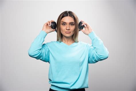 Fille blonde en sweat shirt bleu tenant des écouteurs et s apprête à