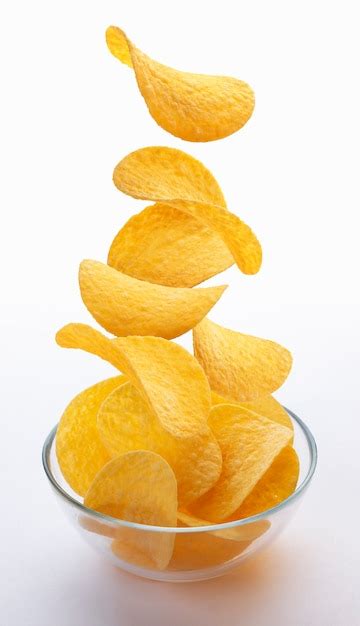 Potato Chips Falling Into Glass Bowl Isolated On White Premium Photo