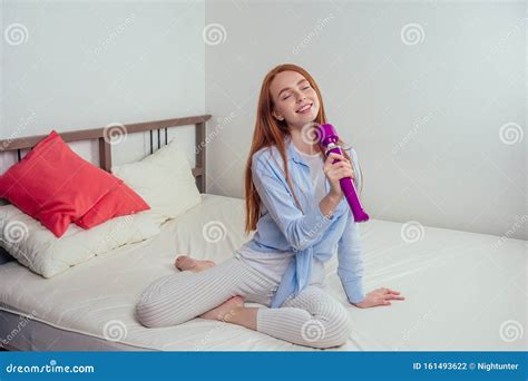 Red Haired Ginger Female Holding Sex Toy Like A Microphone In Bed With Cute Pink Pillows Stock