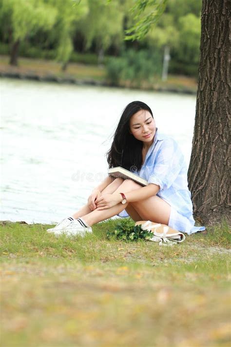 Fille Chinoise Lisant Un Livre Sous L Arbre La Belle Jeune Femme Blonde Avec Le Livre S Asseyent