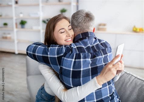 Gadget Addiction Or Infidelity Mature Woman Hugging Husband Stuck In Smartphone Playing