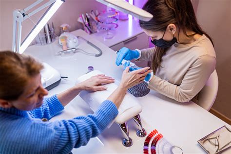 Adult Woman Getting Her Nails Done By Young Female Manicurist At Nail