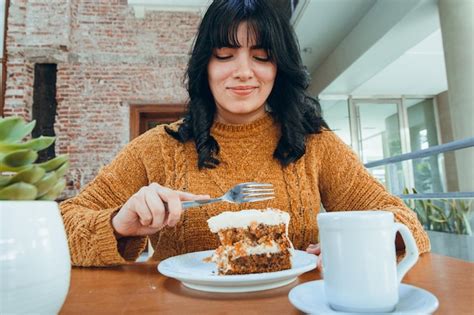Retrato De Una Joven Latina Muy Feliz Sentada Comiendo Pastel De Zanahoria En El Restaurante U