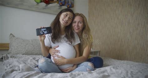 Pregnant Multinational Lesbian Couple Shows At An Ultrasound Image Of His Baby On The Phone