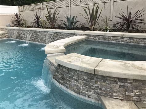 An Outdoor Swimming Pool Surrounded By Stone Walls And Water Features